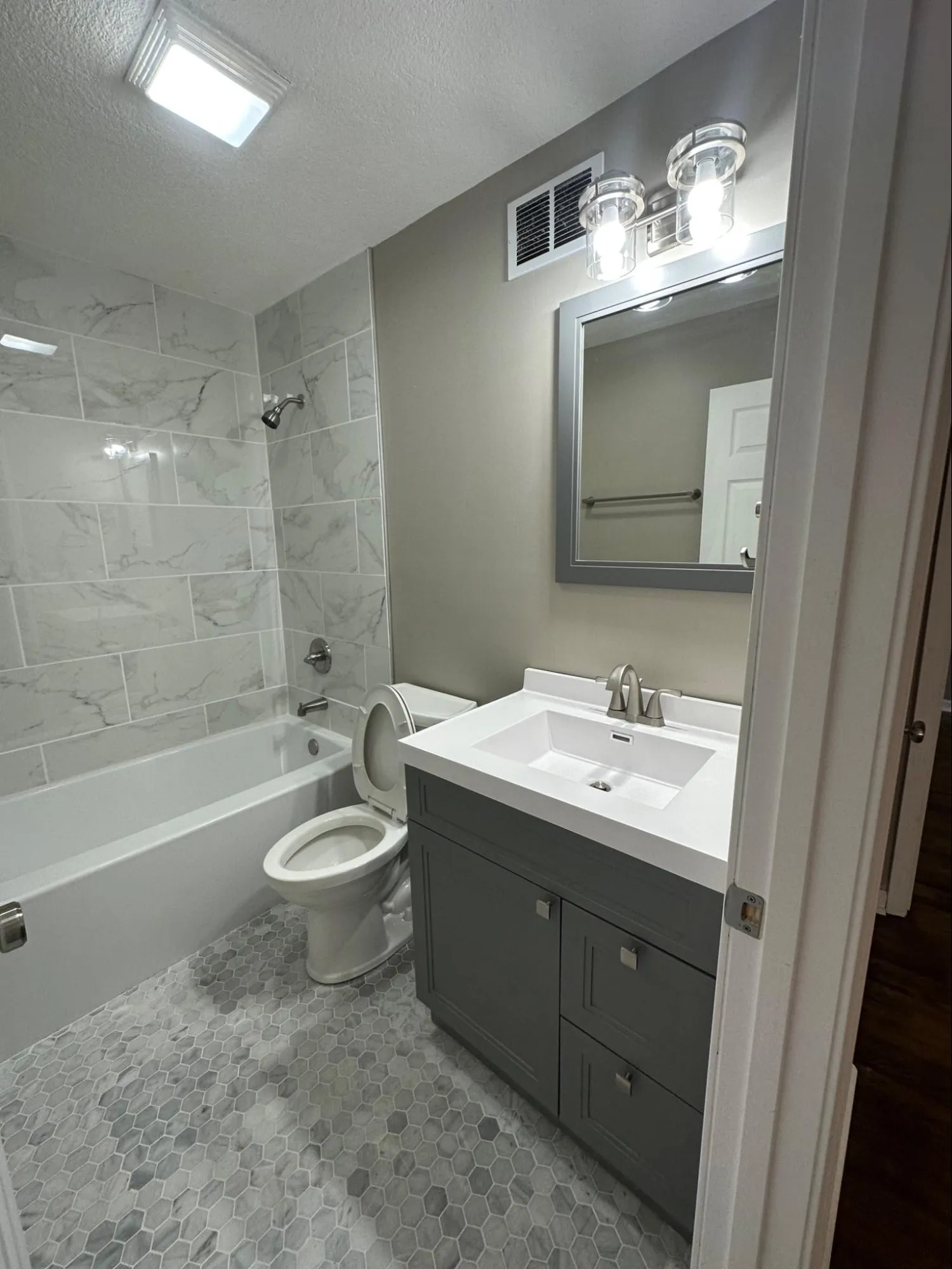 Professional bathroom remodeling featuring marble tile work, vanity cabinet installation, and new faucet