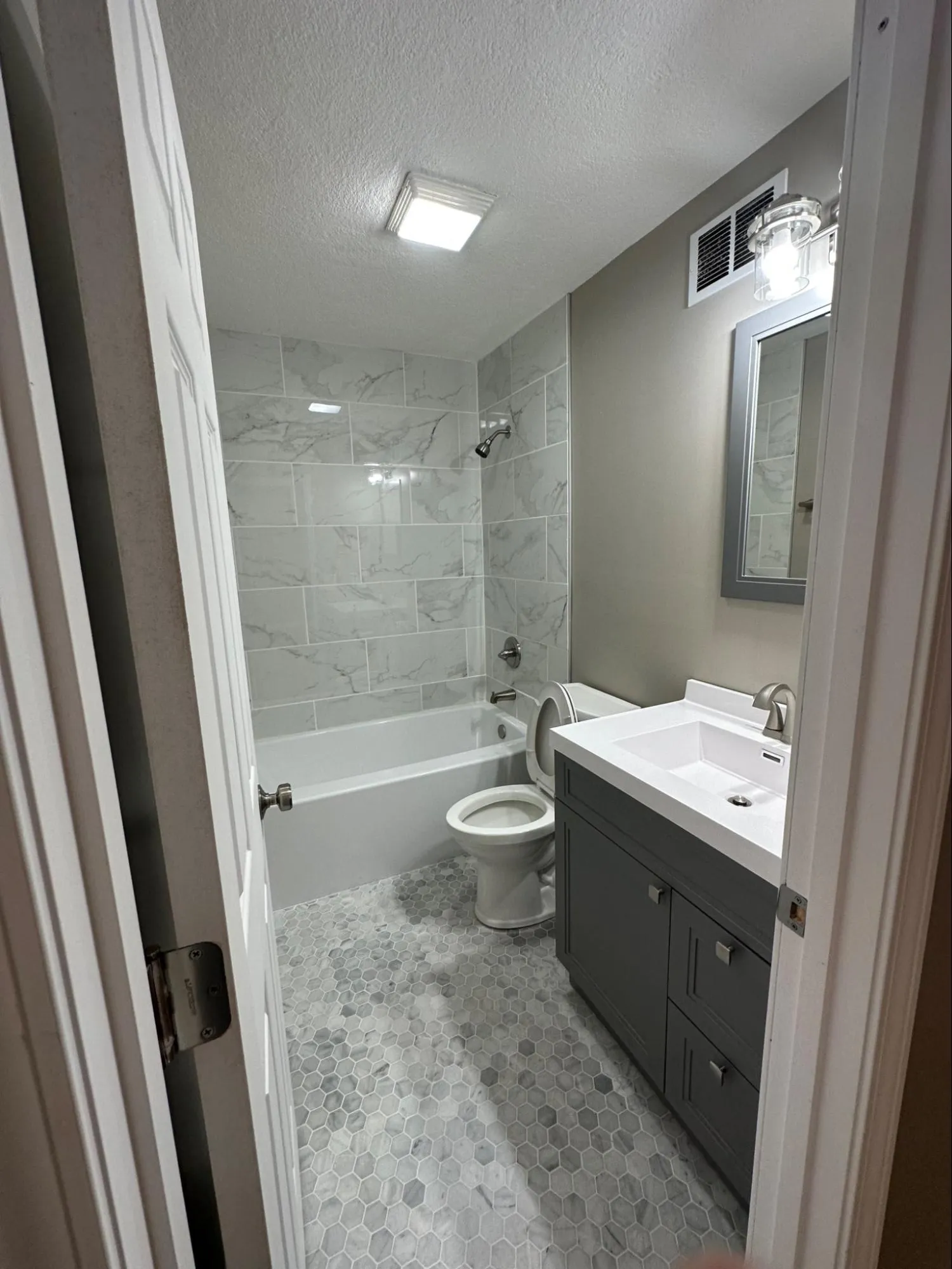 Completed bathroom remodeling with elegant marble-look tile installation and new vanity cabinet
