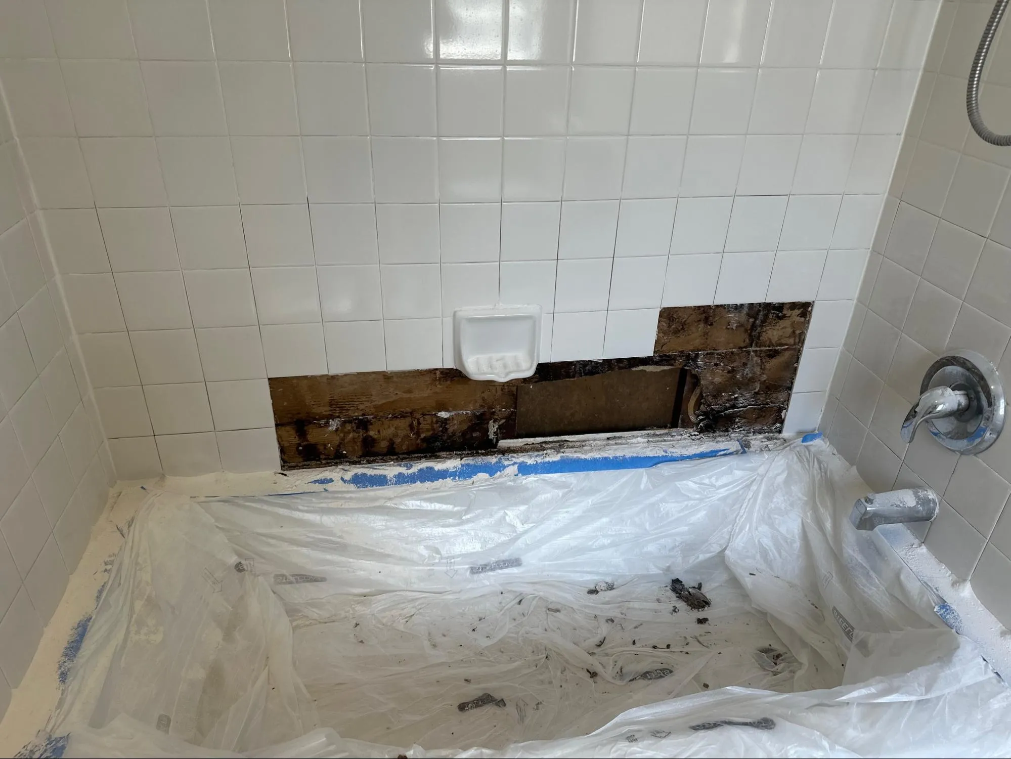 Residential bathroom before renovation with deteriorated vanity cabinet and dated plumbing fixtures
