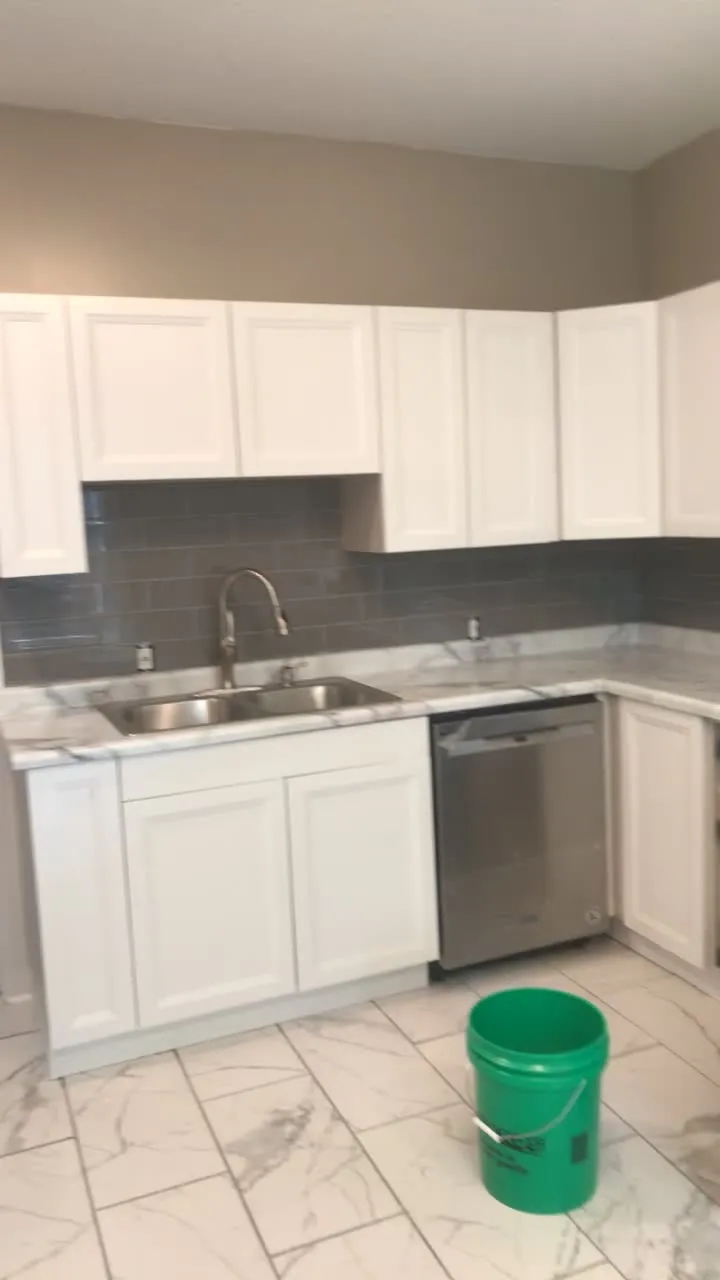 Kitchen before renovation showing dated white cabinets, outdated countertops, and worn flooring requiring remodeling