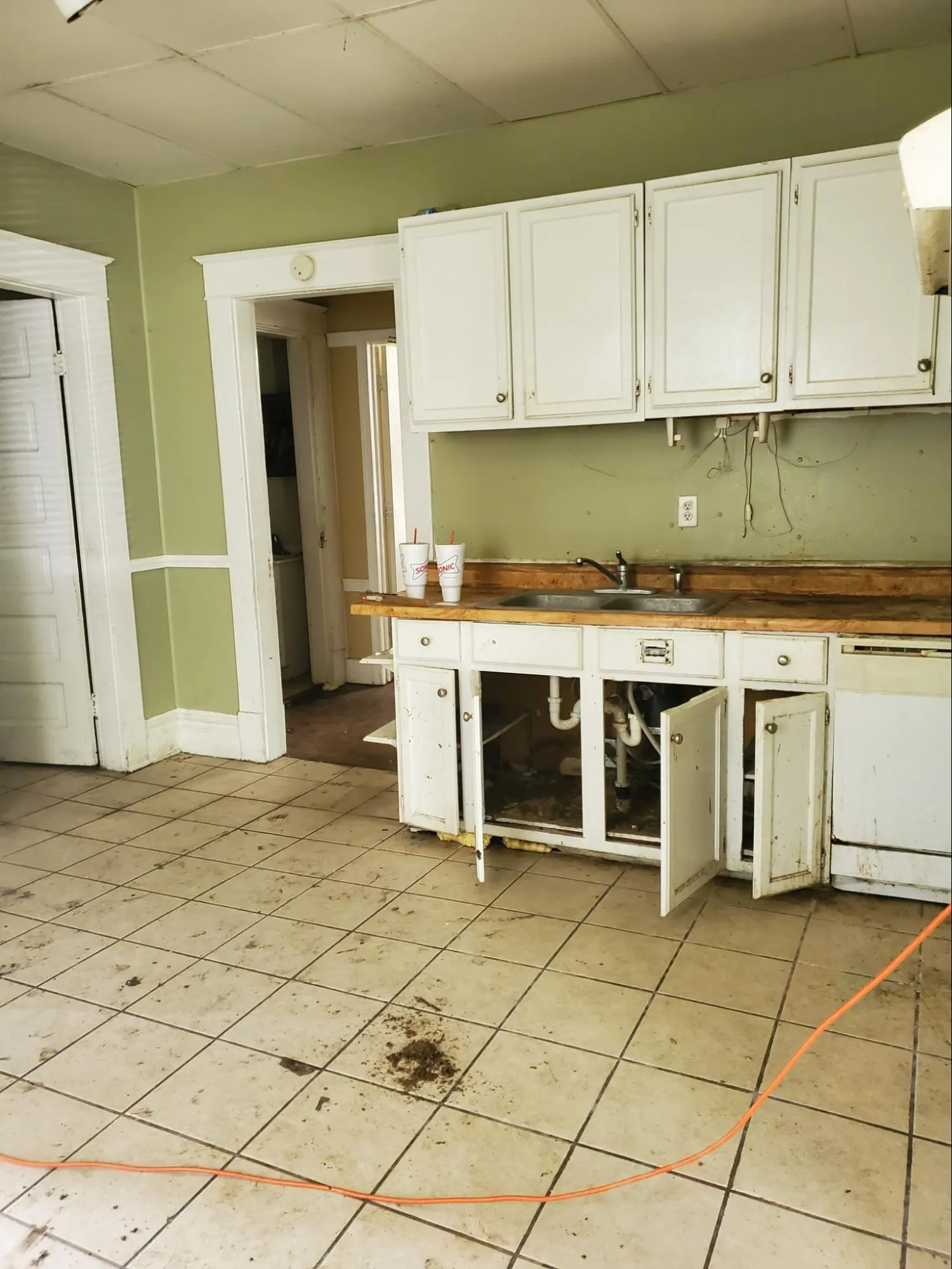 Kitchen before renovation showing outdated appliances, worn cabinetry, and aging countertops