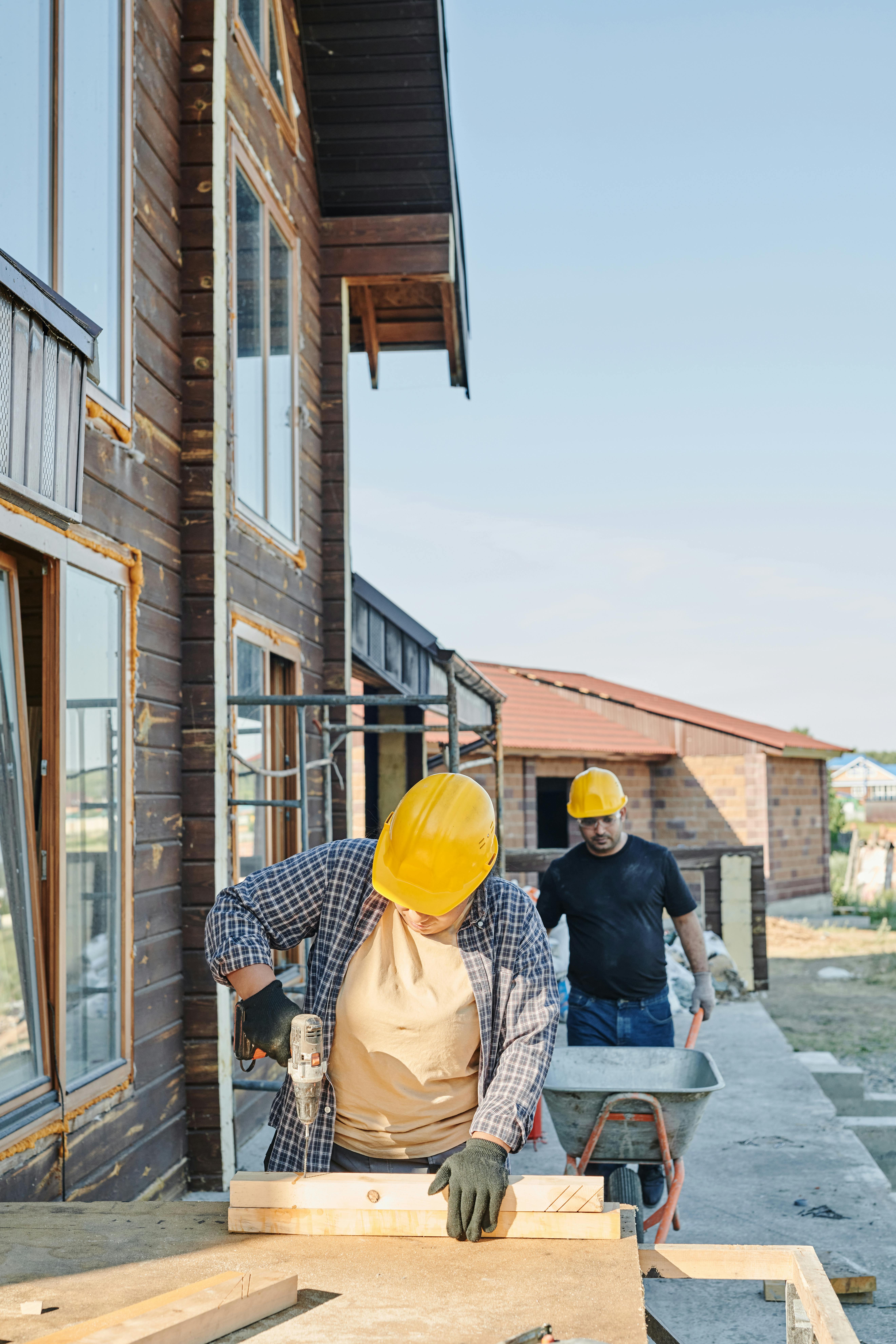Construction workers doing carpentry beside a residential home